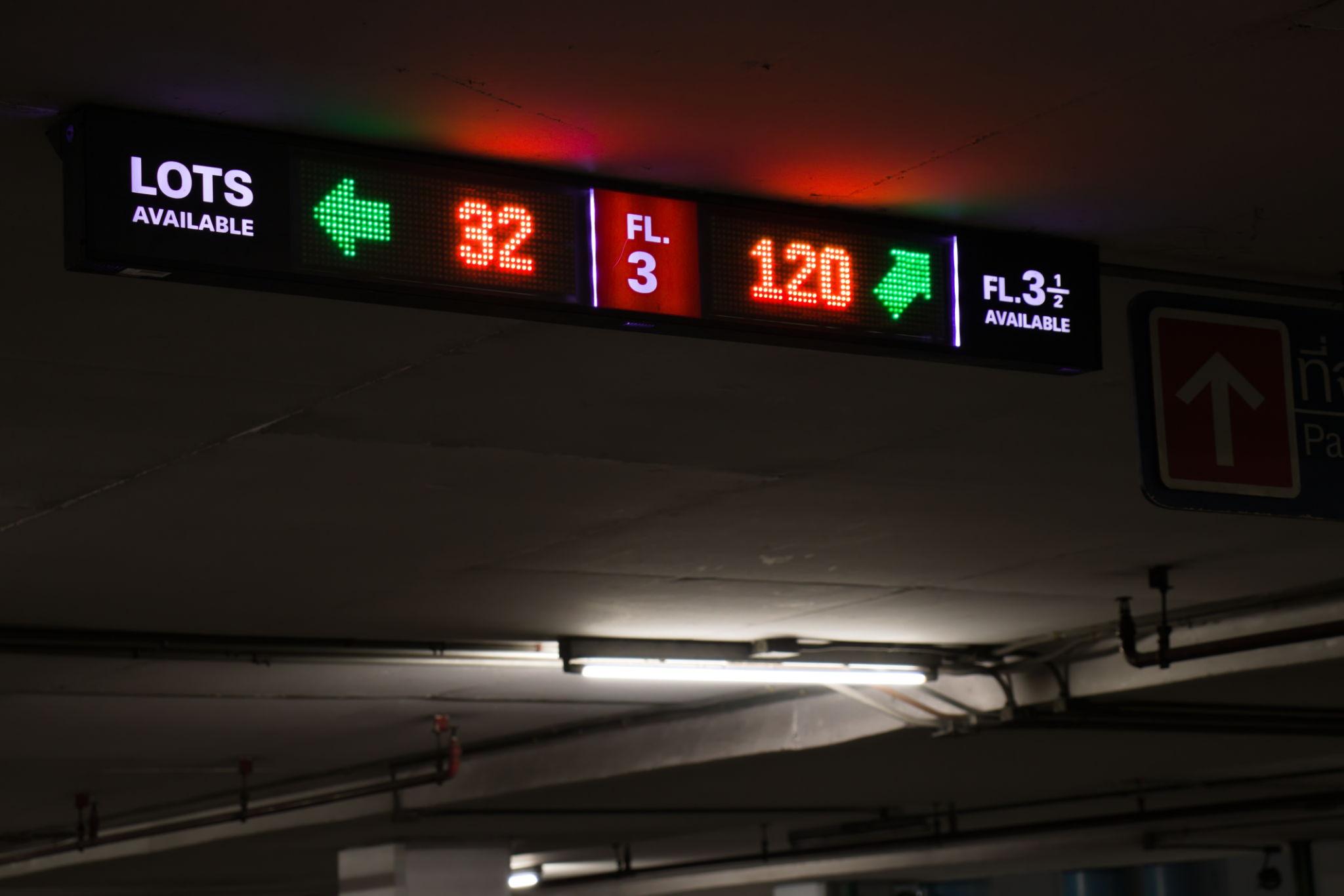 3. Cấu Hình Hệ Thống Màn Hình LED Bãi Giữ Xe Một hệ thống màn hình LED bãi giữ xe thường được thiết kế dựa trên quy mô của bãi đỗ xe, mật độ phương tiện ra vào và vị trí lắp đặt. Đối với các bãi giữ xe tại trung tâm thương mại, tòa nhà văn phòng hoặc khu đô thị lớn, màn hình LED cần đảm bảo khả năng hiển thị rõ ràng từ khoảng cách xa, đồng thời hoạt động ổn định trong thời gian dài. Cấu hình tham khảo của một hệ thống màn hình LED bãi giữ xe thường bao gồm các thông số kỹ thuật như: Diện tích màn hình: 2–20m² Pixel pitch: P3 – P5 (indoor hoặc outdoor tùy vị trí lắp đặt) Độ phân giải: Full HD Độ sáng: 1500–5000 nits Tần số quét: ≥3840Hz Khả năng vận hành: 24/7 Pixel pitch trong khoảng P3 đến P5 giúp nội dung hiển thị rõ ràng khi người lái xe quan sát từ khoảng cách vài mét đến vài chục mét. Đây là yếu tố quan trọng vì người lái xe cần nhanh chóng nhận biết thông tin về số chỗ đỗ xe hoặc hướng dẫn di chuyển trong bãi. Đối với các bãi đỗ xe ngoài trời, màn hình LED thường sử dụng chuẩn chống nước và chống bụi IP65 nhằm đảm bảo khả năng hoạt động ổn định trong điều kiện thời tiết khác nhau như mưa, nắng hoặc độ ẩm cao. Ngoài ra, lớp vỏ bảo vệ và hệ thống tản nhiệt của màn hình cũng được thiết kế đặc biệt để đảm bảo độ bền trong môi trường ngoài trời. Bên cạnh phần cứng hiển thị, hệ thống màn hình LED bãi giữ xe còn được kết nối với phần mềm quản lý bãi xe và hệ thống cảm biến đỗ xe. Các cảm biến được lắp đặt tại từng vị trí đỗ xe để xác định trạng thái còn trống hay đã có xe. Dữ liệu từ cảm biến sẽ được gửi về hệ thống quản lý trung tâm và hiển thị trực tiếp trên màn hình LED. Nhờ hệ thống kết nối này, thông tin về số lượng chỗ đỗ xe còn trống có thể được cập nhật theo thời gian thực, giúp người lái xe dễ dàng tìm kiếm vị trí đỗ xe phù hợp mà không mất nhiều thời gian di chuyển trong bãi. 4. 6 Lợi Ích Khi Sử Dụng Màn Hình LED Bãi Giữ Xe Việc triển khai màn hình LED bãi giữ xe mang lại nhiều lợi ích thiết thực cho cả đơn vị quản lý bãi xe và người sử dụng. Thứ nhất, màn hình LED giúp hiển thị số lượng chỗ đỗ xe còn trống một cách rõ ràng và trực quan. Người lái xe có thể nhanh chóng nhận biết khu vực còn chỗ trống ngay từ cổng vào bãi xe. Thứ hai, hệ thống LED giúp hướng dẫn xe ra vào bãi đỗ xe một cách thuận tiện và an toàn. Các thông tin như hướng di chuyển, khu vực đỗ xe hoặc lối ra có thể được hiển thị rõ ràng trên màn hình. Thứ ba, màn hình LED giúp giảm thời gian tìm kiếm chỗ đỗ xe. Khi thông tin được hiển thị rõ ràng ngay từ đầu, người lái xe sẽ không cần di chuyển nhiều vòng trong bãi, từ đó giảm tình trạng ùn tắc giao thông nội bộ. Thứ tư, hệ thống hiển thị LED có thể tích hợp với hệ thống quản lý bãi xe thông minh, cho phép cập nhật dữ liệu tự động và giảm sự phụ thuộc vào việc kiểm tra thủ công. Thứ năm, màn hình LED bãi giữ xe có thể được sử dụng để trình chiếu quảng cáo hoặc thông tin dịch vụ. Điều này giúp tạo thêm nguồn thu từ quảng cáo cho đơn vị quản lý bãi xe. Thứ sáu, việc sử dụng màn hình LED giúp nâng cao hình ảnh hiện đại và chuyên nghiệp của bãi giữ xe. Điều này đặc biệt quan trọng đối với các trung tâm thương mại, sân bay hoặc khu đô thị cao cấp. 5. Ứng Dụng Thực Tế Của Màn Hình LED Bãi Giữ Xe Trong thực tế, màn hình LED bãi giữ xe có thể được lắp đặt tại nhiều vị trí khác nhau nhằm hỗ trợ việc quản lý và hướng dẫn phương tiện. Tại cổng vào bãi xe, màn hình LED thường được sử dụng để hiển thị tổng số chỗ đỗ xe còn trống trong toàn bộ bãi. Thông tin này giúp người lái xe quyết định có nên vào bãi xe hay tìm vị trí khác nếu bãi đã đầy. Trong khu vực bên trong bãi xe, các màn hình LED kích thước nhỏ hơn có thể được lắp đặt tại các ngã rẽ hoặc khu vực phân làn. Những màn hình này hiển thị hướng dẫn di chuyển hoặc số lượng chỗ đỗ xe còn trống tại từng khu vực cụ thể. Tại cổng ra bãi xe, màn hình LED có thể hiển thị thông tin thanh toán, hướng dẫn lối ra hoặc các thông báo quan trọng từ ban quản lý bãi xe. Ngoài ra, tại các trung tâm thương mại, sân bay hoặc tòa nhà văn phòng, màn hình LED bãi giữ xe còn được sử dụng để trình chiếu quảng cáo, thông tin sự kiện hoặc các dịch vụ tiện ích trong khu vực. Nhờ lượng người qua lại lớn, các vị trí này có giá trị quảng cáo cao. 6. Xu Hướng Bãi Đỗ Xe Thông Minh Và Màn Hình LED Trong xu hướng phát triển của Smart City (thành phố thông minh), hệ thống bãi đỗ xe đang dần được tích hợp với nhiều công nghệ hiện đại nhằm tối ưu hóa việc quản lý và sử dụng không gian đỗ xe. Màn hình LED đóng vai trò là thiết bị hiển thị trung tâm giúp truyền tải thông tin từ hệ thống quản lý bãi xe đến người sử dụng. Khi kết hợp với các công nghệ như cảm biến đỗ xe, camera giám sát và hệ thống quản lý dữ liệu, màn hình LED có thể hiển thị thông tin chính xác về tình trạng bãi xe theo thời gian thực. Ngoài ra, các hệ thống bãi đỗ xe thông minh còn có thể tích hợp với ứng dụng di động hoặc hệ thống định vị, giúp người lái xe tìm kiếm vị trí đỗ xe ngay trước khi đến bãi. Khi đến nơi, màn hình LED sẽ tiếp tục hướng dẫn người lái xe đến đúng vị trí còn trống. Bên cạnh đó, hệ thống LED còn có thể kết nối với nền tảng quảng cáo kỹ thuật số, cho phép hiển thị nội dung quảng cáo theo từng khung giờ hoặc theo đối tượng khách hàng. Điều này giúp tối ưu hóa giá trị thương mại của bãi giữ xe. 7. Kết Luận Màn hình LED bãi giữ xe là giải pháp hiển thị hiện đại giúp nâng cao hiệu quả quản lý và cải thiện trải nghiệm của người sử dụng bãi đỗ xe. Nhờ khả năng hiển thị thông tin rõ ràng, cập nhật theo thời gian thực và vận hành ổn định trong thời gian dài, hệ thống LED giúp việc quản lý bãi xe trở nên thuận tiện và hiệu quả hơn. Việc ứng dụng màn hình LED không chỉ giúp giảm tình trạng ùn tắc trong bãi đỗ xe mà còn góp phần nâng cao hình ảnh hiện đại và chuyên nghiệp của các công trình như trung tâm thương mại, sân bay hoặc tòa nhà văn phòng. Trong tương lai, khi các hệ thống Smart Parking tiếp tục phát triển và được triển khai rộng rãi, màn hình LED sẽ trở thành một thành phần quan trọng trong hạ tầng bãi đỗ xe thông minh, góp phần tối ưu hóa việc quản lý giao thông đô thị và nâng cao chất lượng dịch vụ cho người sử dụng.